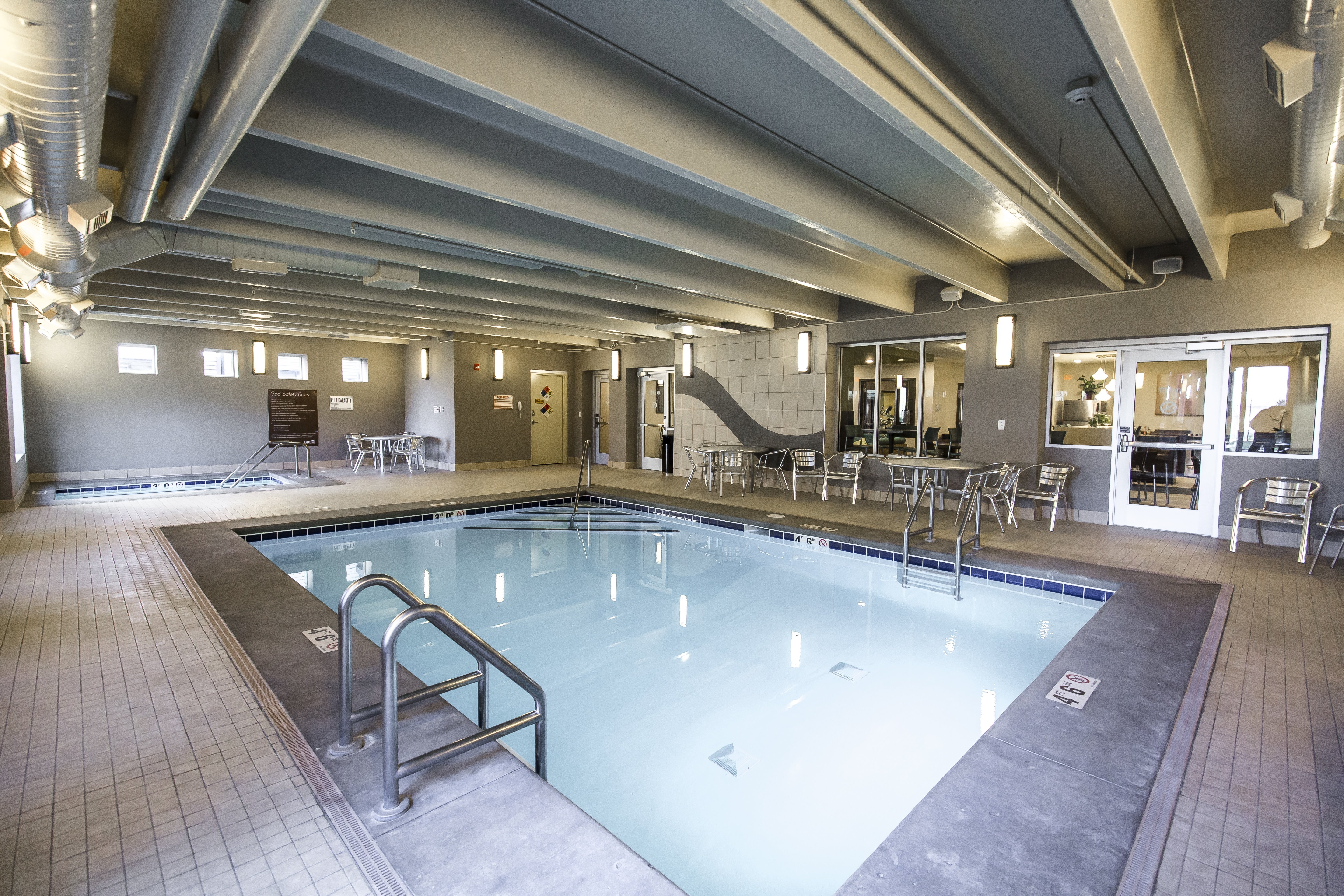 A large indoor swimming pool with a metal ladder.